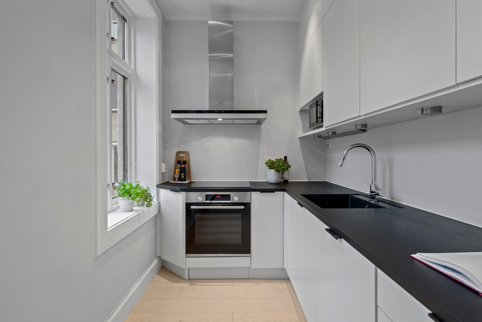 Innredningen har glatte, hvite fronter fra 2019, mørk benkeplate og sort, nedfelt vaskekum (2019). Det er montert spotbelysning under overskap. Integrerte hvitevarer inkluderer induksjonstopp og stekeovn (2021), kombinert kjøl/frys (2019) samt oppvaskmask Galleribilde