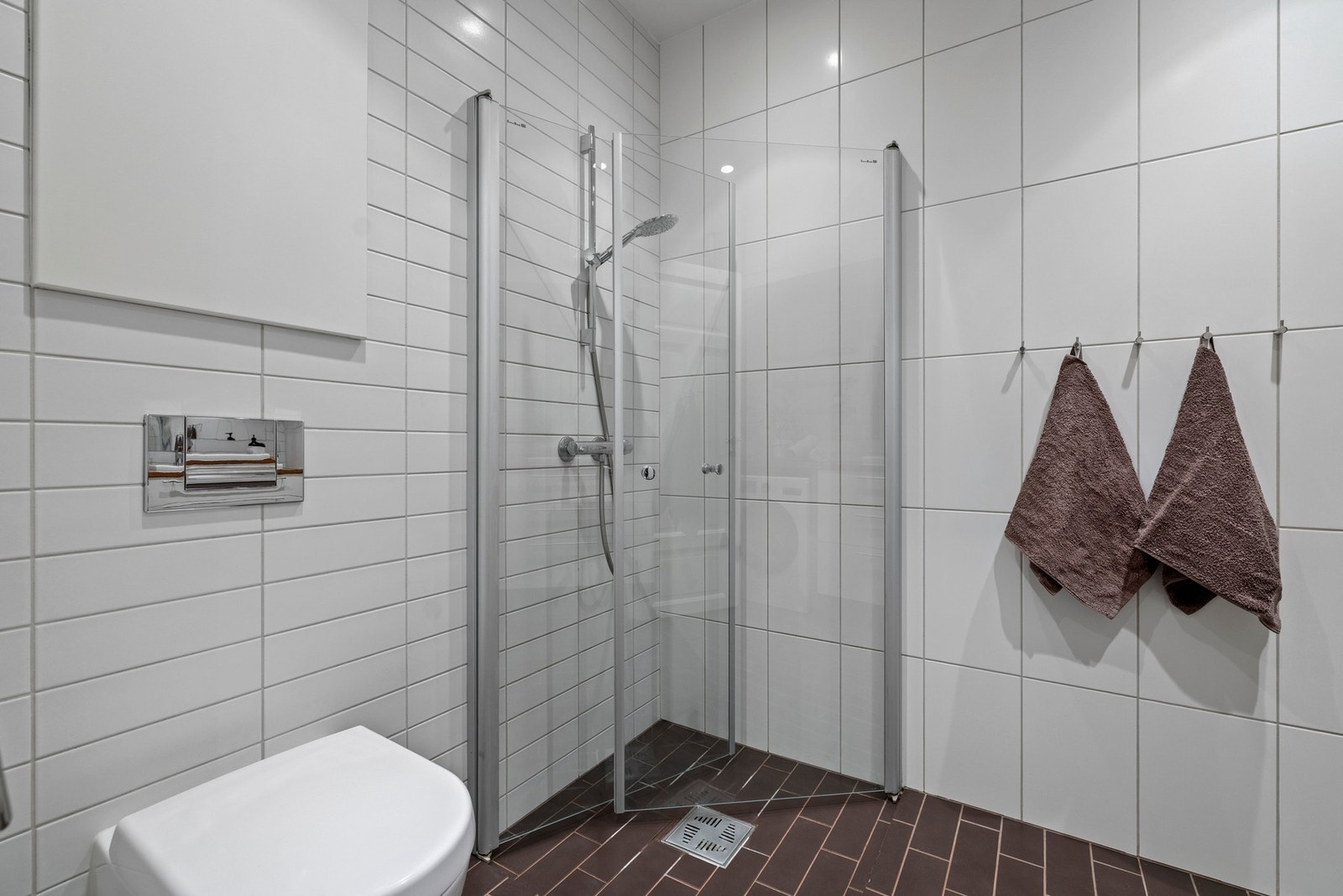 Innredningen består av servant nedfelt i heltre benkeplate av eik, med hvit skuffeseksjon og opplegg for vaskemaskin under. Videre er badet utstyrt med veggmontert toalett, dusjhjørne med innfellbare glassdører, speil med belysning og tre vegghyller. Galleribilde