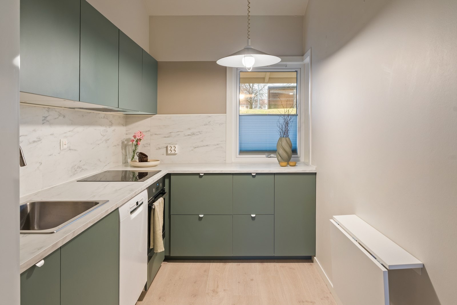 Kjøkkenet har glatte fronter og en slitesterk laminatbenkeplate Galleribilde