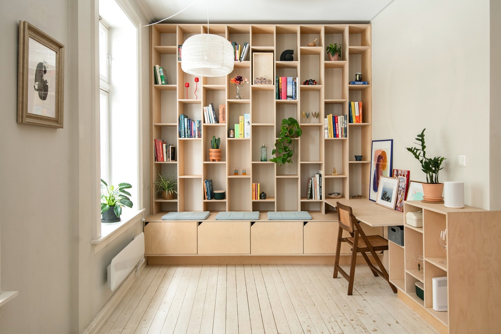 En spesialtegnet reol i bjørkefinér, utført etter arkitektens tegninger, byr på en kombinasjon av åpne hyller og lukkede oppbevaringsløsninger. Galleribilde