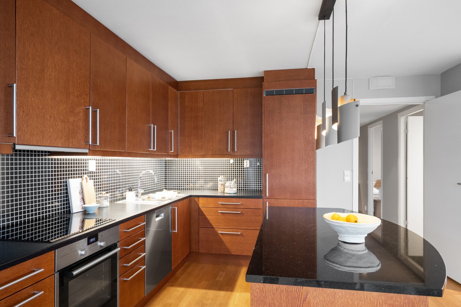 Innredningen har gylne, glatte fronter, takhøyde skap og mørke benkeplater Galleribilde