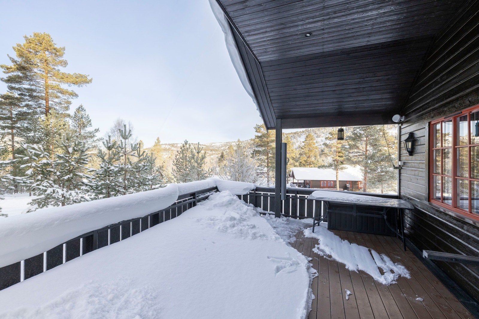 Terrassen byr på god plass til utemøbler og hyggelige samlinger, med utsyn mot nærliggende hytter og skog. Galleribilde