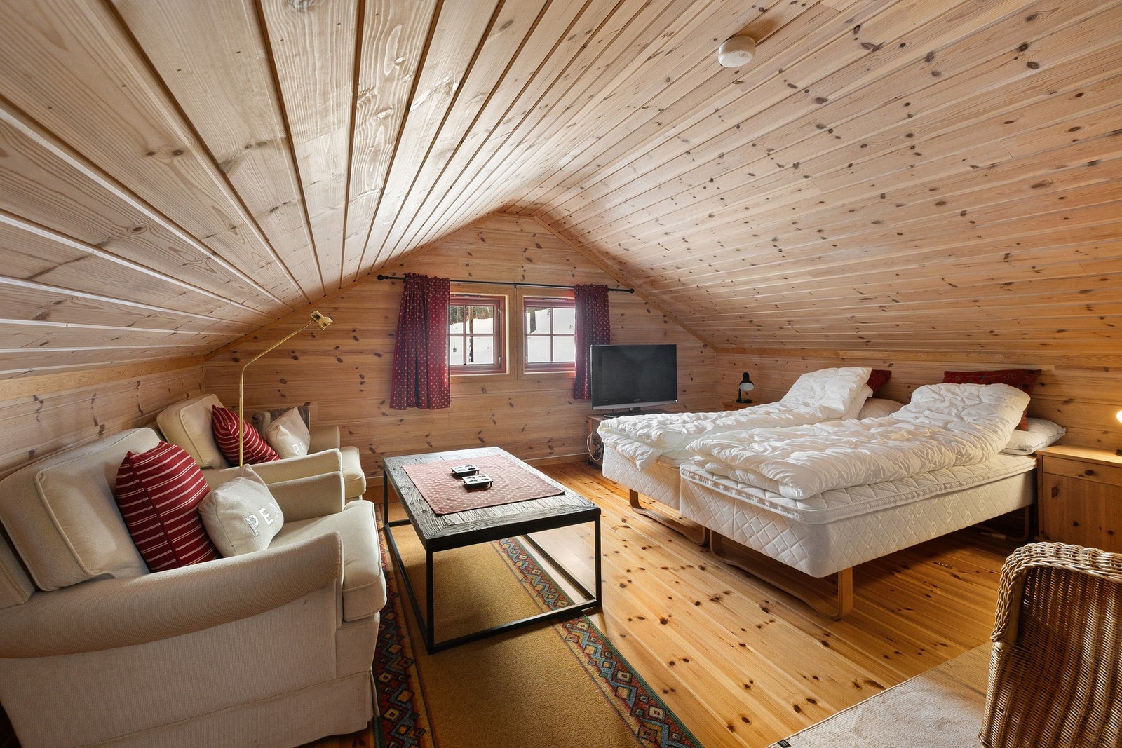 Hemsen er perfekt for å trekke seg tilbake etter en dag ute i naturen. Her er det plass til både avslapning med film, spill eller en god bok. De skrå himlingene og trepanelte overflatene skaper en lun og ekte hyttefølelse. Galleribilde