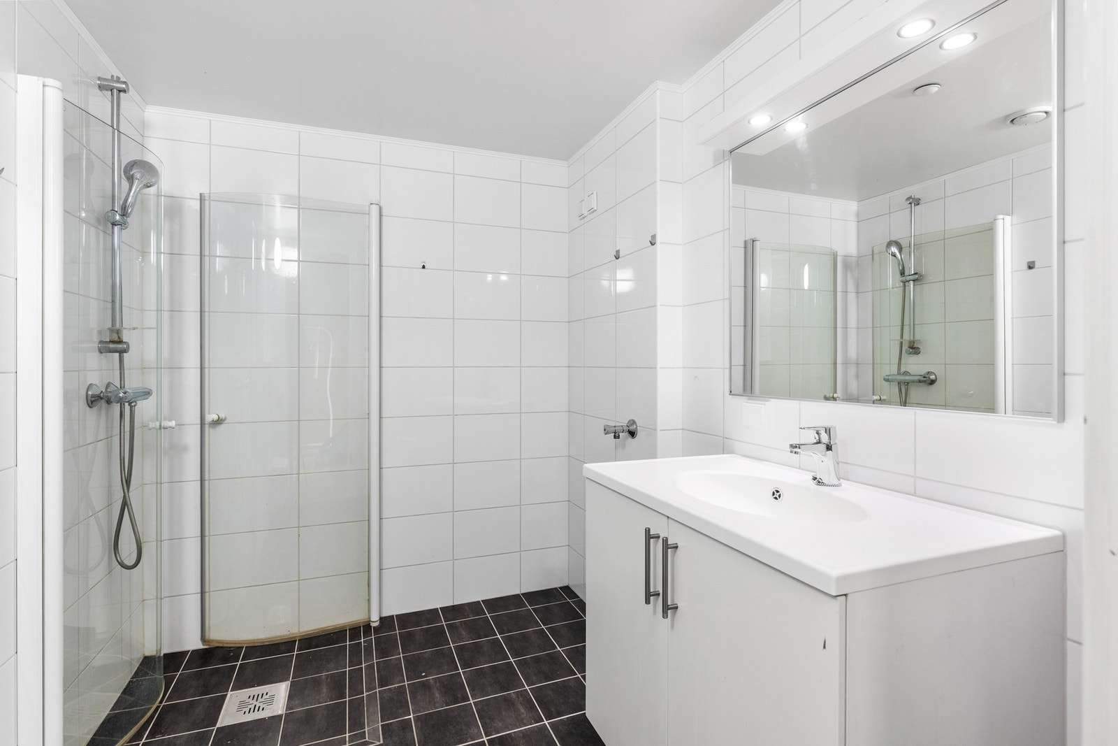 Flislagt baderom med gulvvarme, opplegg for vaskemaskin, veggmontert wc, innfellbare dusjdører, servant og servantskap. Galleribilde