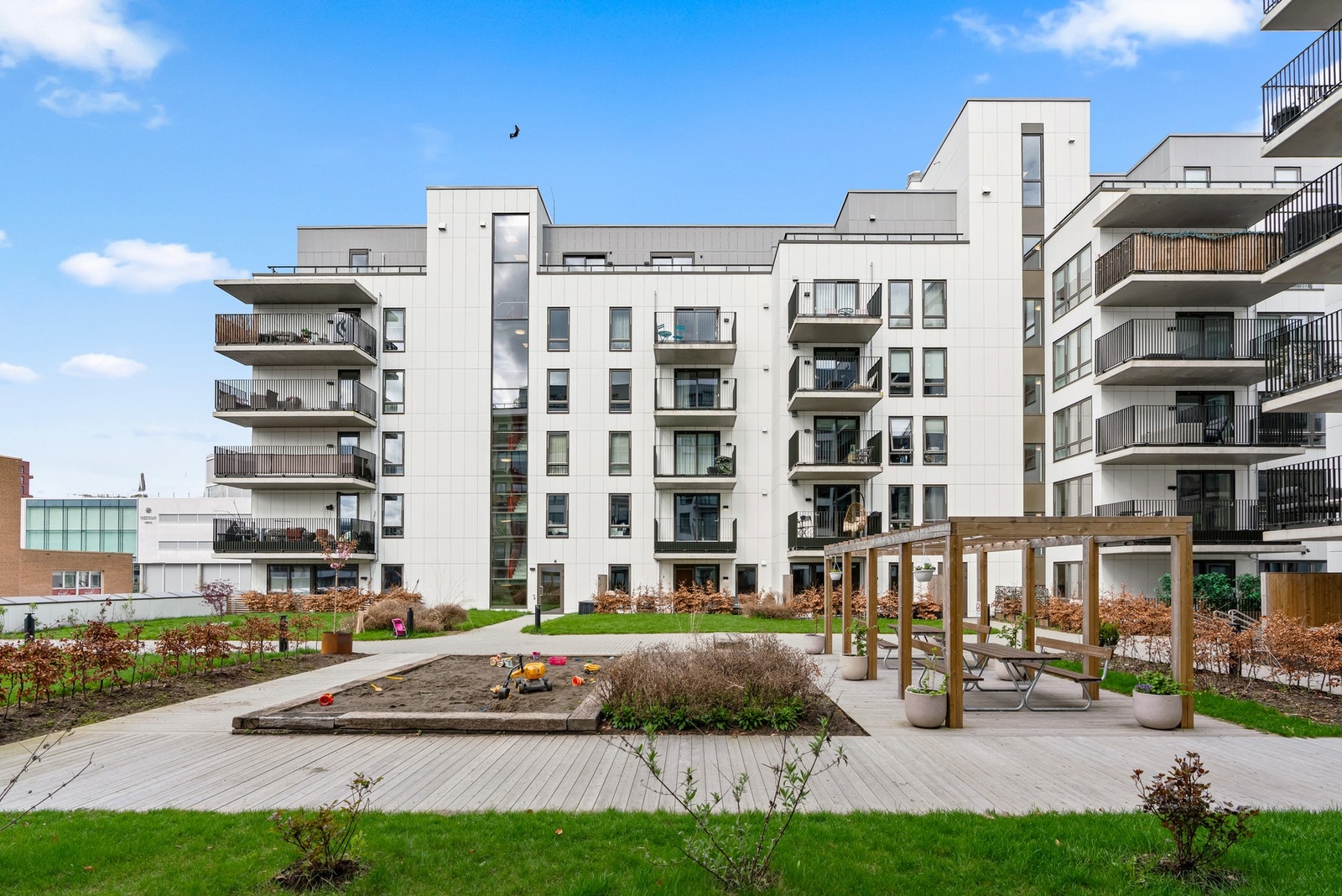 Hyggelig gårdsrom med lekeplass, sittegrupper og pergola. Galleribilde