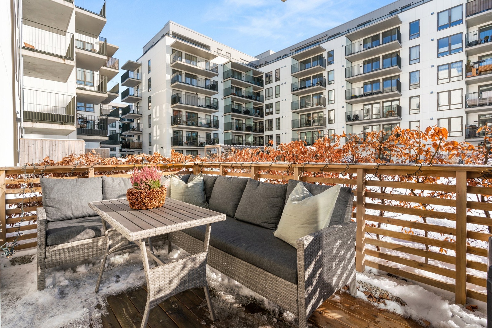 Utsyn mot flott gårdsrom. Terrassen er omringet av gjerde og frodige busker. Galleribilde