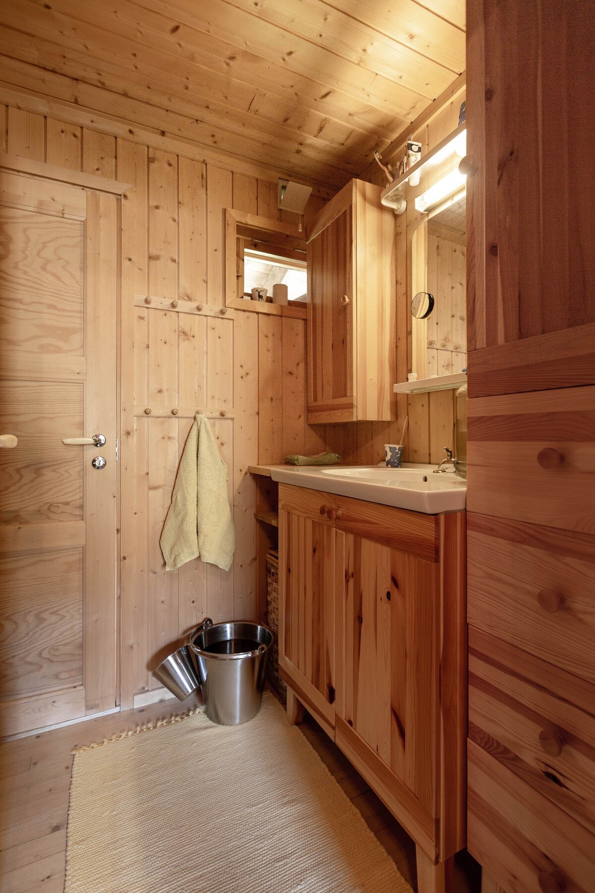 Baderomsinnredning med vaskeservant samt overskap, speil og lys (lys fra solcelleanlegg). Galleribilde