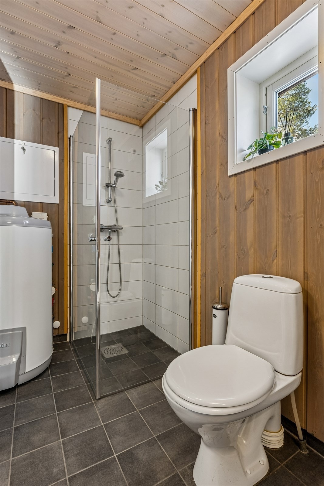 Dusjhjørne med innfellbare glassdører og flislagt gulv med varmekabler. Galleribilde