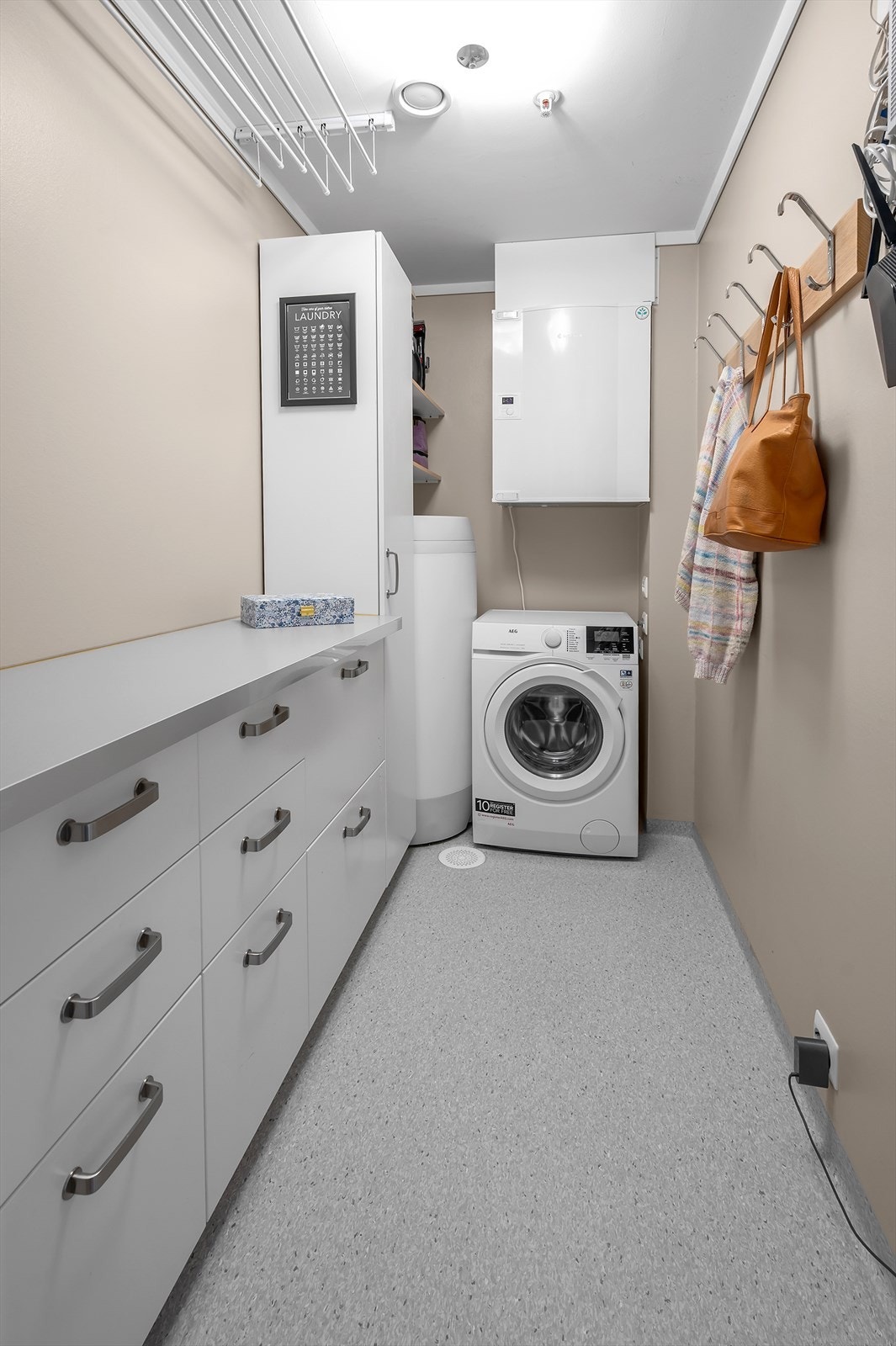 Vaskerommet er funksjonelt og praktisk med god oppbevaringsplass. Veggene er kledd med malte plater, taket er malt, og gulvet har vinylbelegg som er enkelt å holde rent. Galleribilde