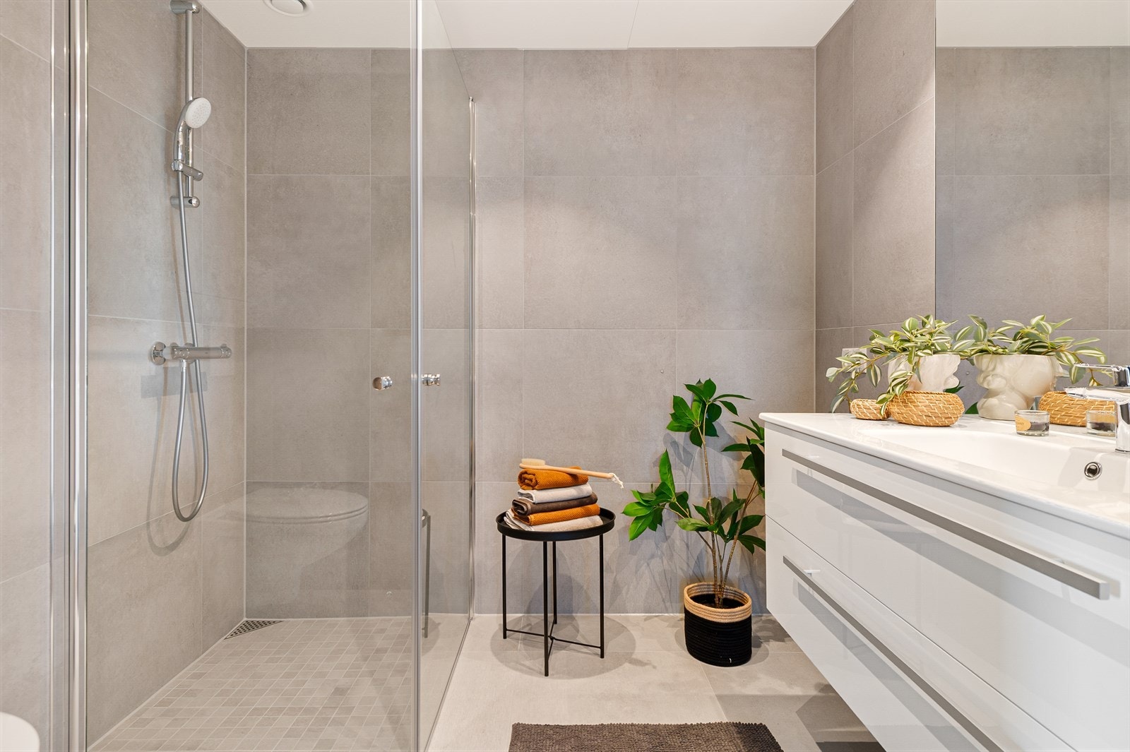 Moderne bad med store, lyse fliser og gulvvarme. Galleribilde