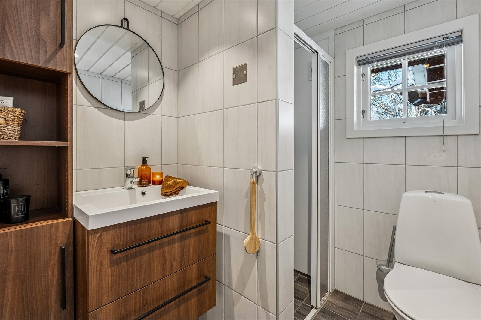 Hyttas bad er lyst og delikat med flislagt gulv med varmekabler. Det er også flislagte vegger, med unntak av i dusjhjørnet hvor det er baderomsplater og glassdør/vegger. Galleribilde