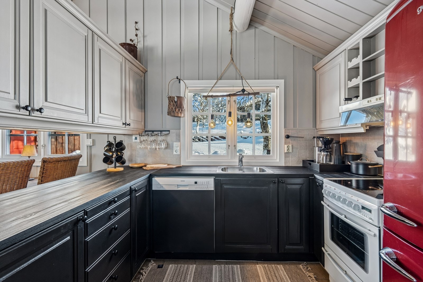 Kjøkkeninnredningen har godt med skap- og benkeplass, og fliser mellom overskap og benk. Integrert ventilator og oppvaskmaskin, frittstående komfyr og kjøle-/fryseskap. Galleribilde