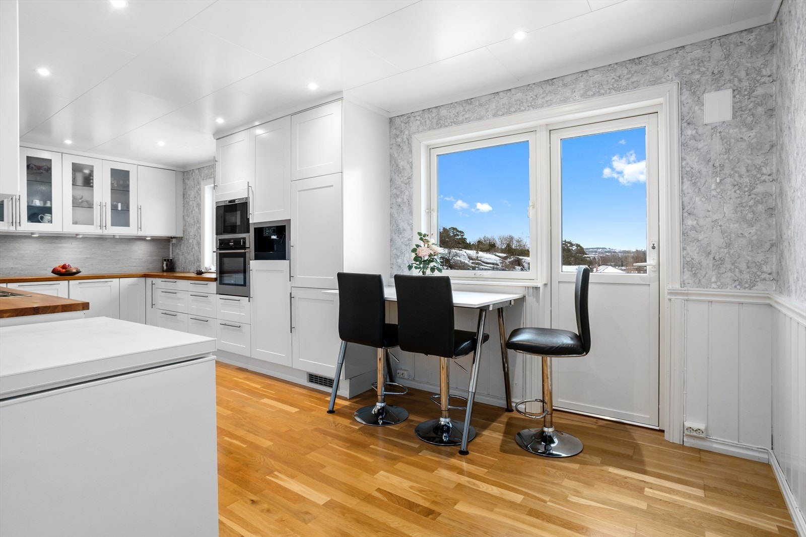 En liten og koselig sittegruppe på kjøkkenet gir rommet en innbydende atmosfære og gjør det enkelt å nyte dagens små måltider Galleribilde