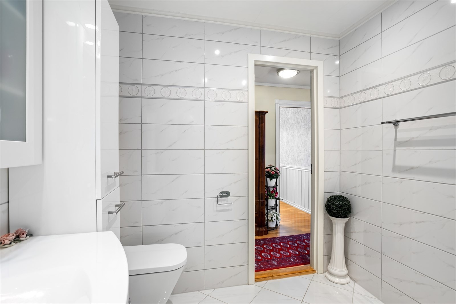 Rommet er innredet med nedfelt servant i praktisk baderomsinnredning, veggmontert toalett og dusjkabinett Galleribilde