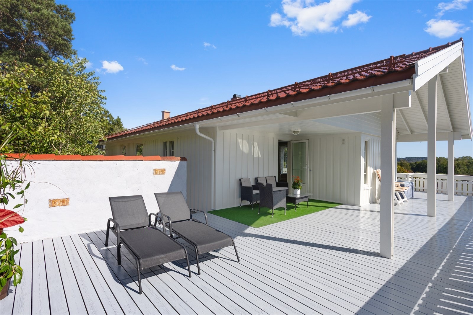 Det er stor veranda/balkong som strekker seg rundt til fremsiden av boligen. Galleribilde