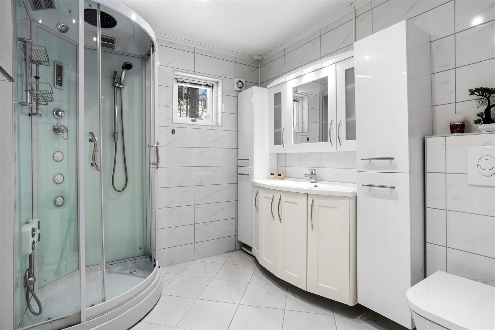 Badet har et moderne og rent uttrykk med fliser på både vegger og gulv, kombinert med himlingsplater i taket Galleribilde