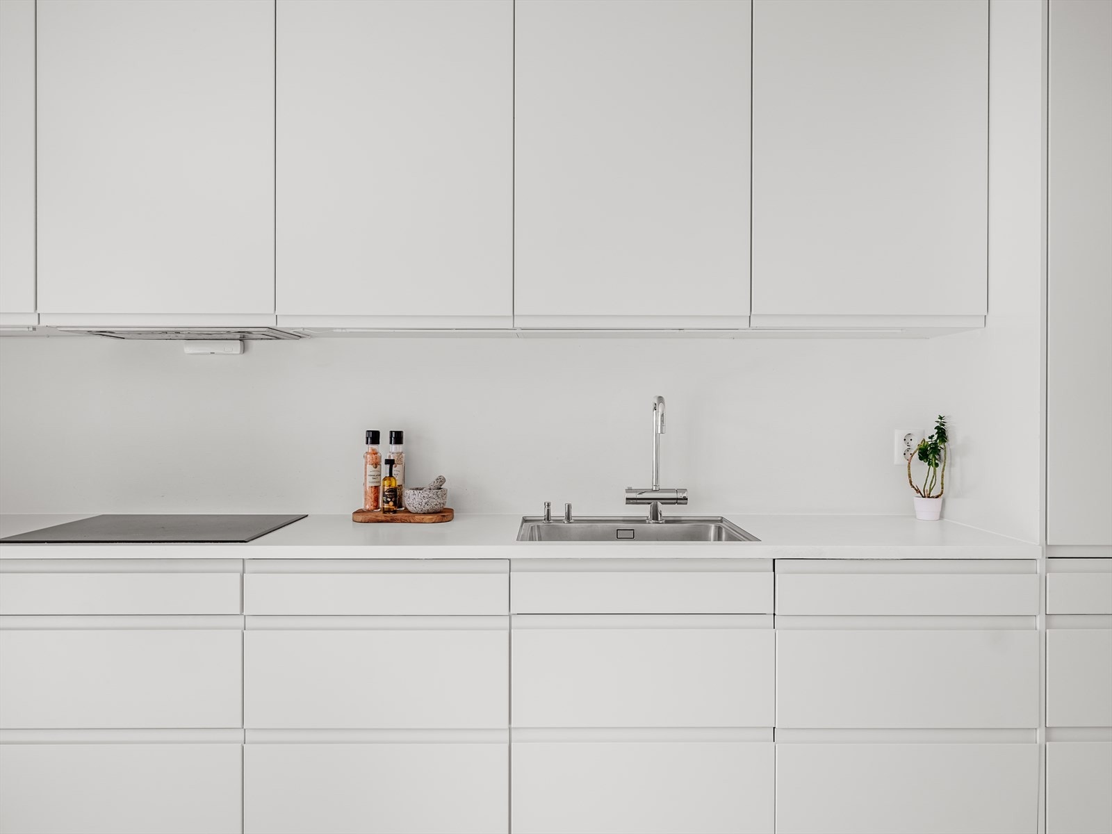 Moderne og velutstyrt Sigdal-kjøkken med integrerte hvitevarer. Innredningen har glatte fronter og laminat benkeplate med nedfelt oppvaskkum i rustfritt stål Galleribilde