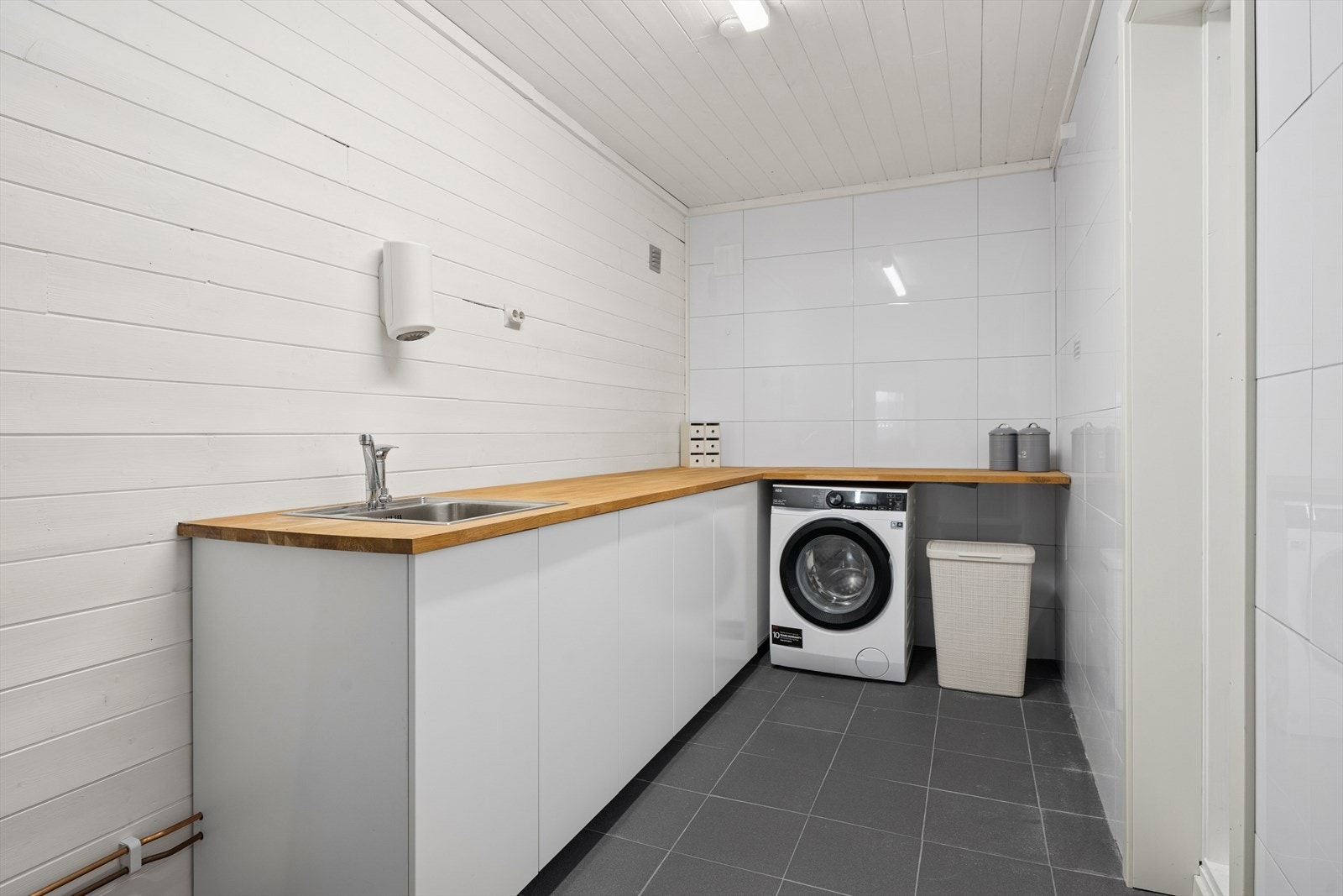 Vaskerommet er utvidet ved at den innerste boden er fjernet. Rommet er ikke bruksendret fra tilleggsdel til hoveddel. Galleribilde