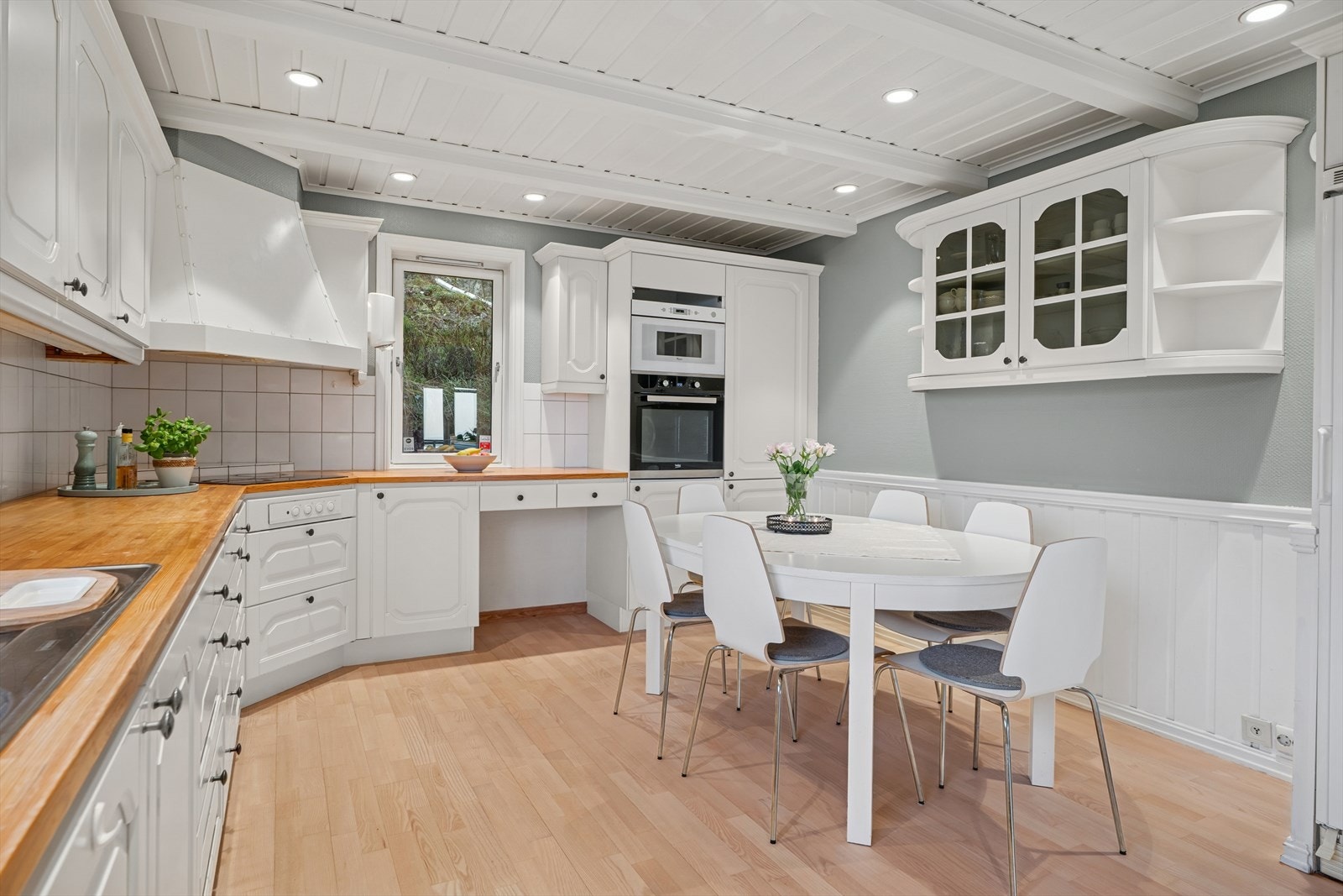 Hjemmets kjøkken har innredning med hvite, profilerte fronter og en benkeplate i heltre med planlimt vask i rustfritt stål. Stekeovn (2018) på kjøkken. Galleribilde