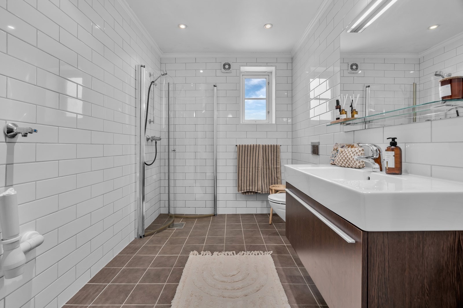 Leiligheten har et romslig flislagt bad i tidløse fargevalg Galleribilde