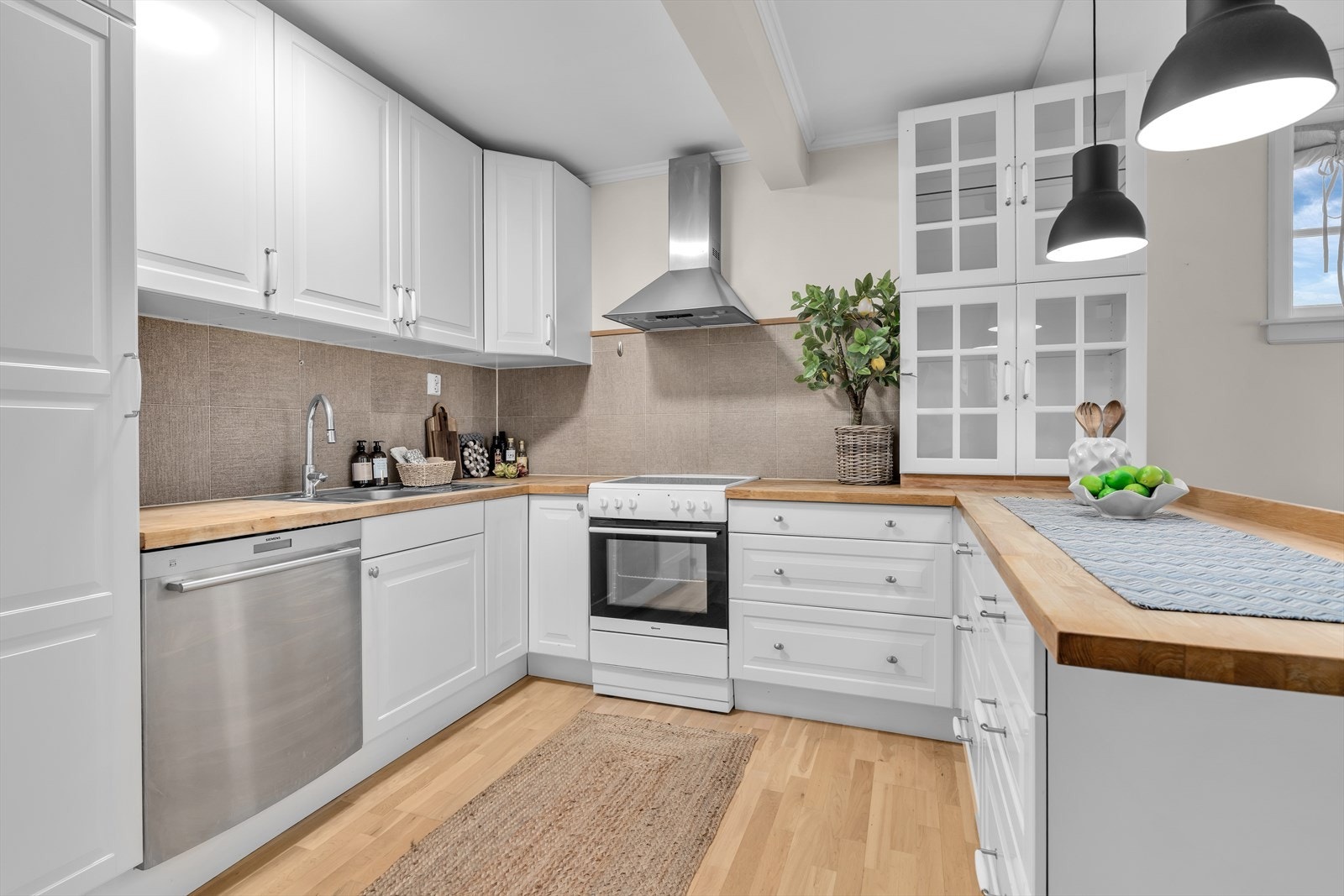 Kjøkkenet har innredning med profilerte fronter, enkelte overskap med glassfelt og heltre benkeplate Galleribilde