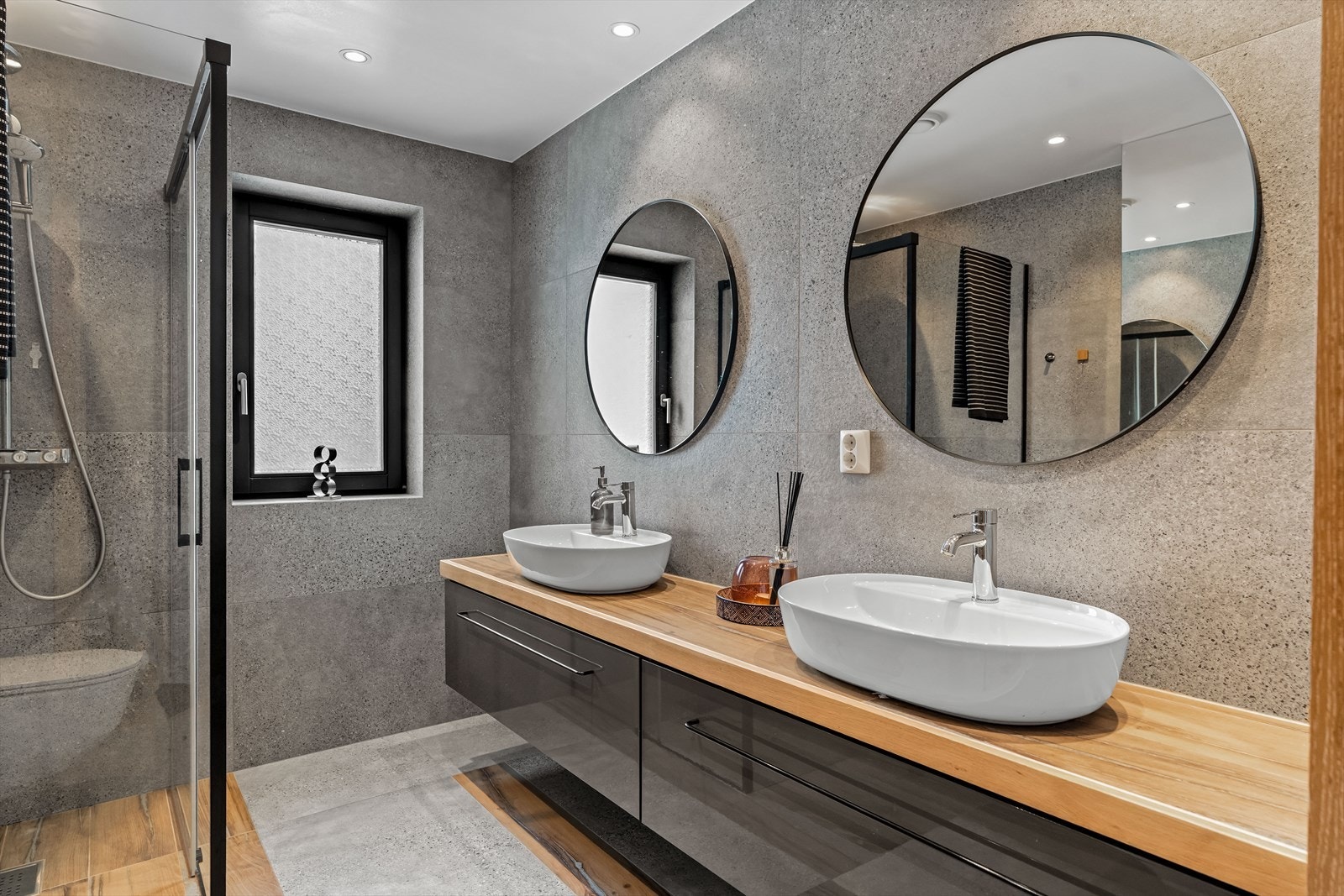 Elegant baderomsinnredning med runde speil og varme materialvalg. Galleribilde