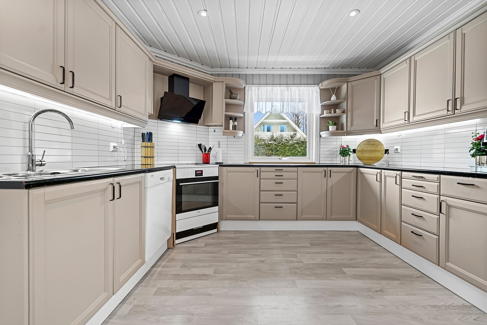 Kjøkkenet er innredet med profilerte fronter og laminat benkeplate. Frittstående komfyr, kjøleskap og fryseskap, underbygget oppvaskmaskin. Galleribilde