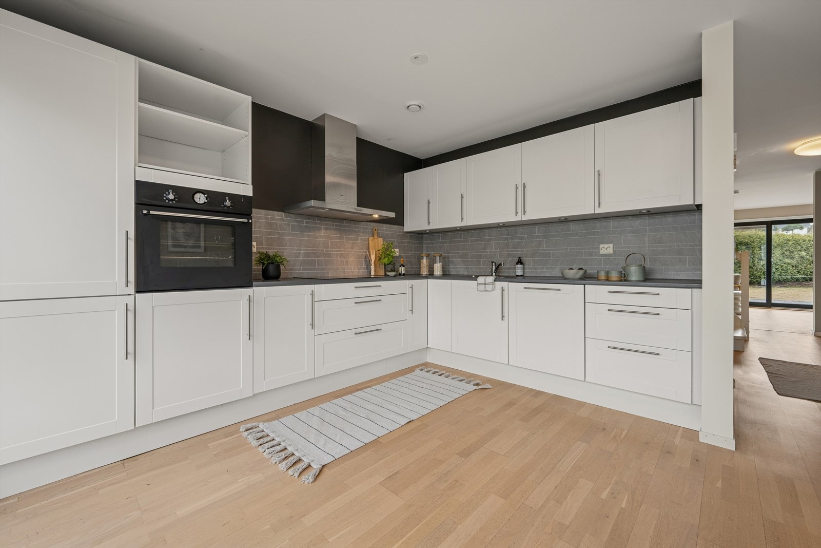 Kjøkkenet er stilrent innredet med hvite, profilerte fronter og grå benkeplate i laminat. Et stort og godt kjøkken hvor man har rikelig med skap- og skuffeplass, samt gode arbeidsflater på benk. Galleribilde