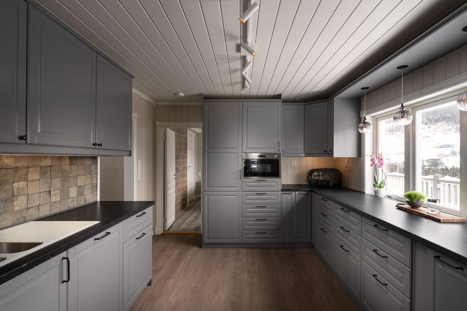 Romslig kjøkken med profilerte fronter, laminert benkeplate og integrerte hvitevarer. Galleribilde