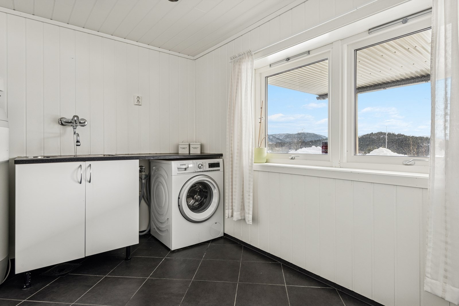 Separat vaskerom med flislagt gulv, utslagsvask og opplegg for vaskemaskin. Galleribilde