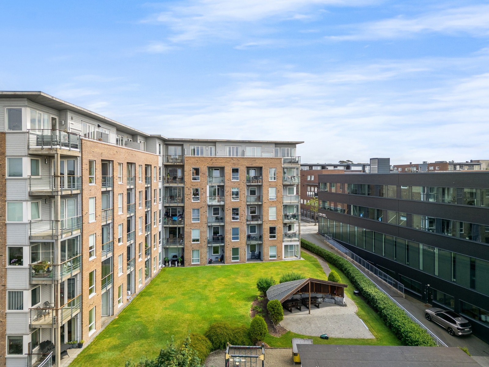 Boligens fellesarealer er godt tilrettelagt med grønne plener, gapahuk og flere sittebenker, noe som skaper et hyggelig og brukervennlig uteområde. Galleribilde