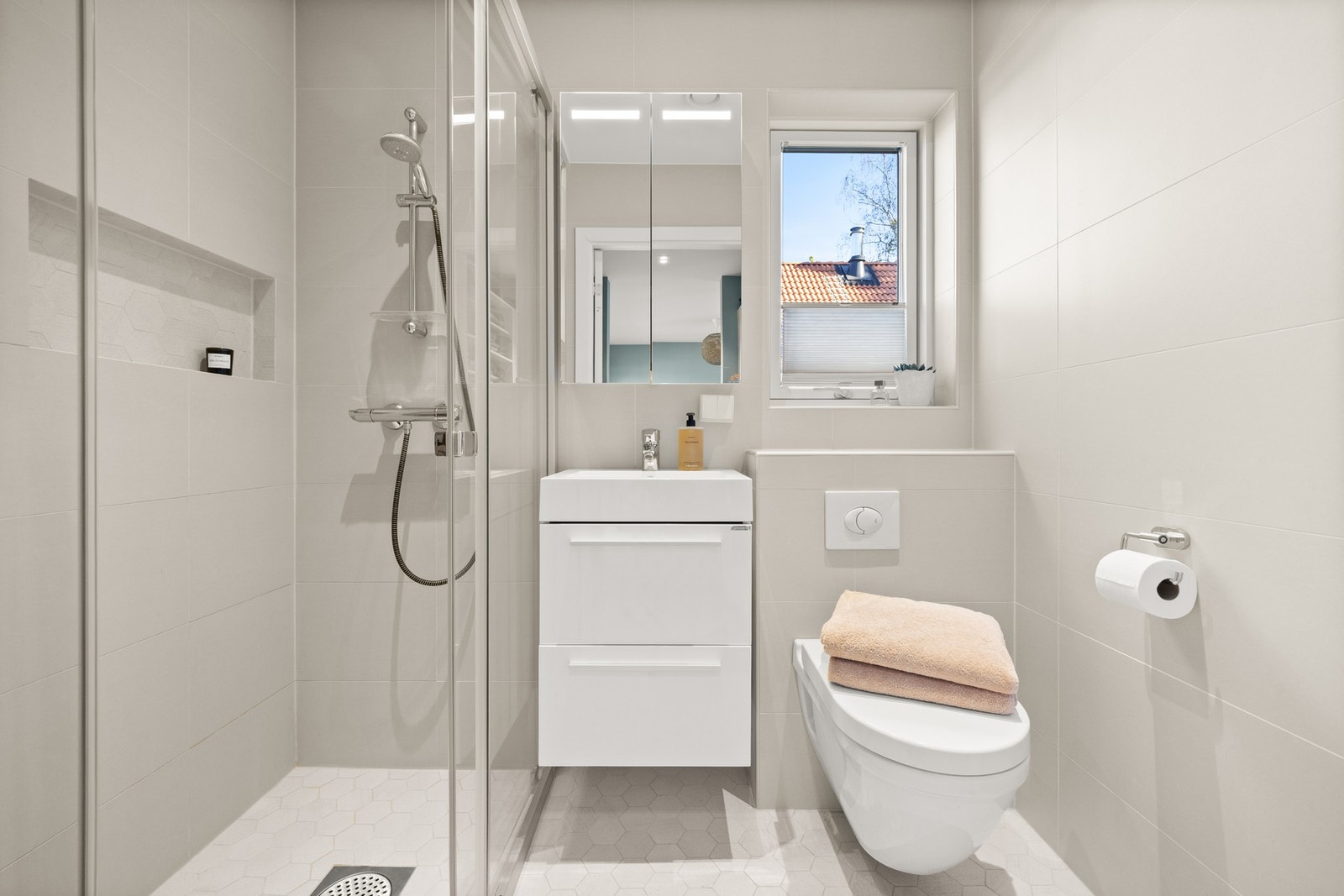 Et praktisk og stilrent, flislagt bad med behagelige varmekabler i gulvet. Galleribilde