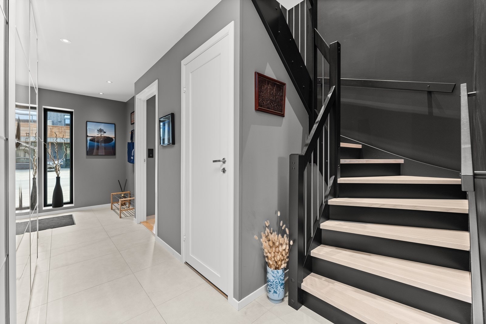 Malt trapp med eiketrinn og stålspiler fører opp til stue/kjøkken. Praktisk bod ved trappen. Galleribilde