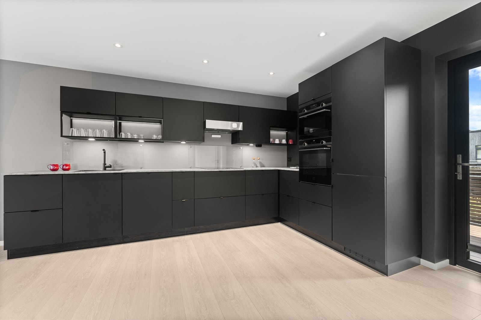 Kjøkkenet har slette fronter og integrerte hvitevarer (kjøleskap, oppvaskmaskin, stekeovn, mikroovn og koketopp). Galleribilde