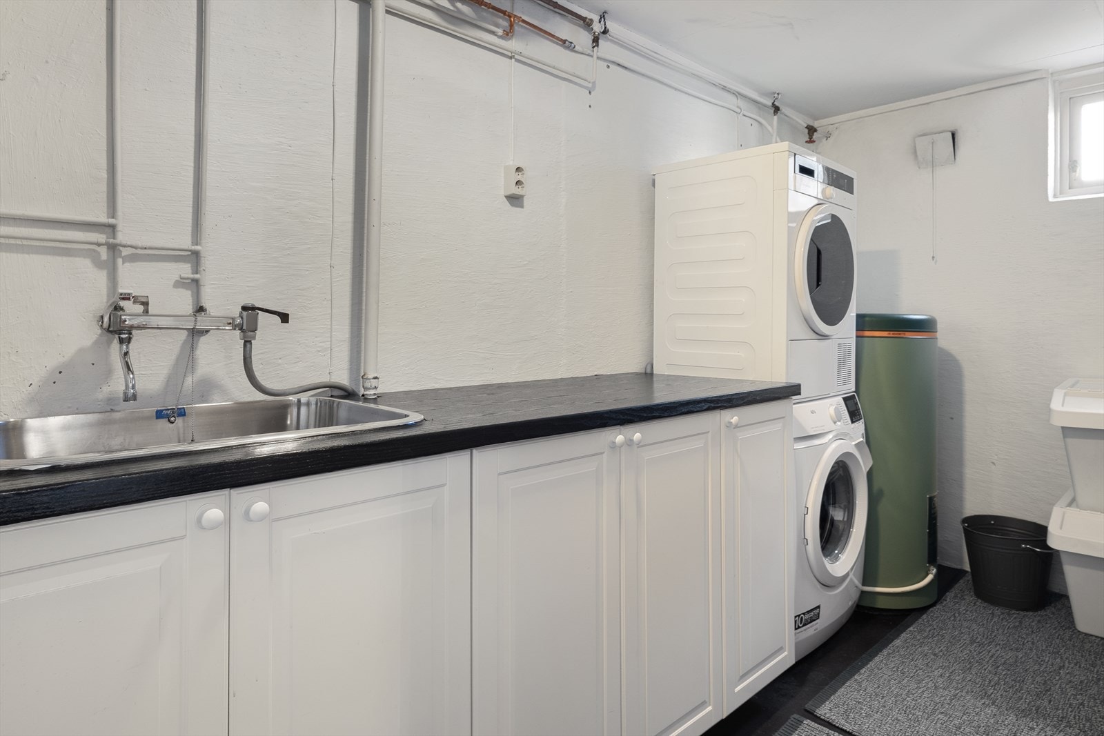 Vaskerom med praktisk innredning, nedfelt vaskekum og opplegg for vaskemaskin. Galleribilde