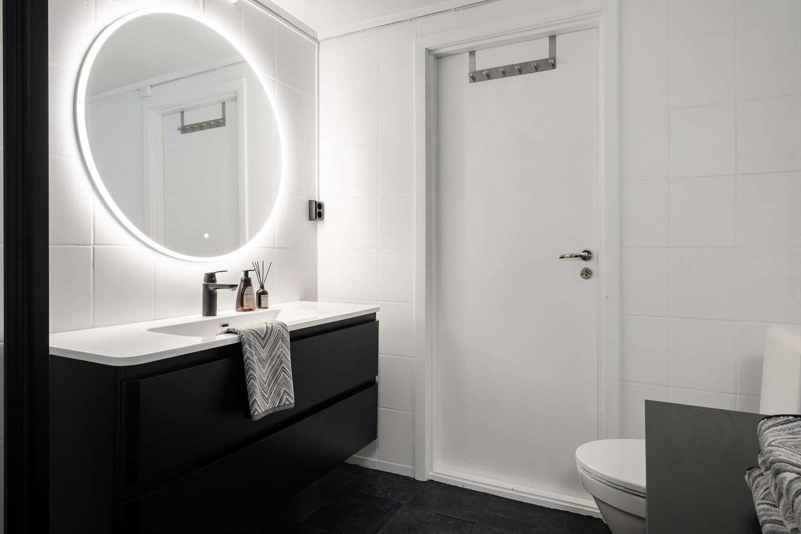 Innredningen består av et moderne servantskap med servant, et gulvmontert toalett og et dusjkabinett. Galleribilde