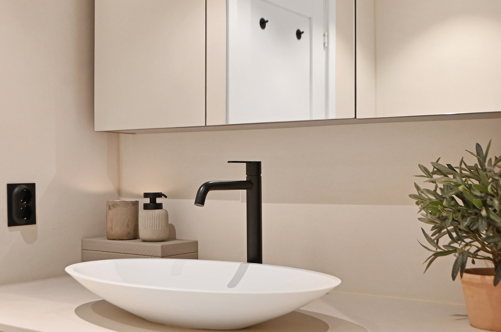 Moderne baderomsinnredning med toppmontert servant og sorte armaturer. Plass til vaskemaskin og tørketrommel under servant. Galleribilde