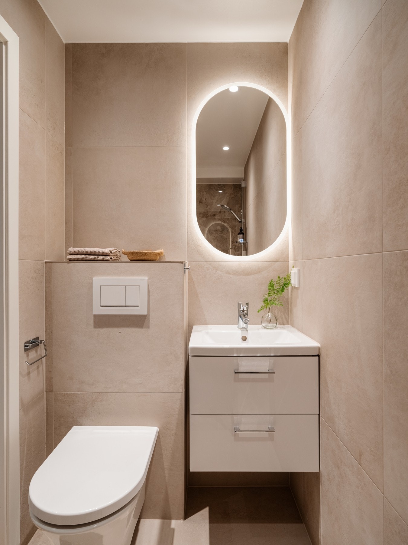 Badet er innredet med dusjnisje, vegghengt toalett, servantseksjon med skuffer og speil med integrert lys. Galleribilde