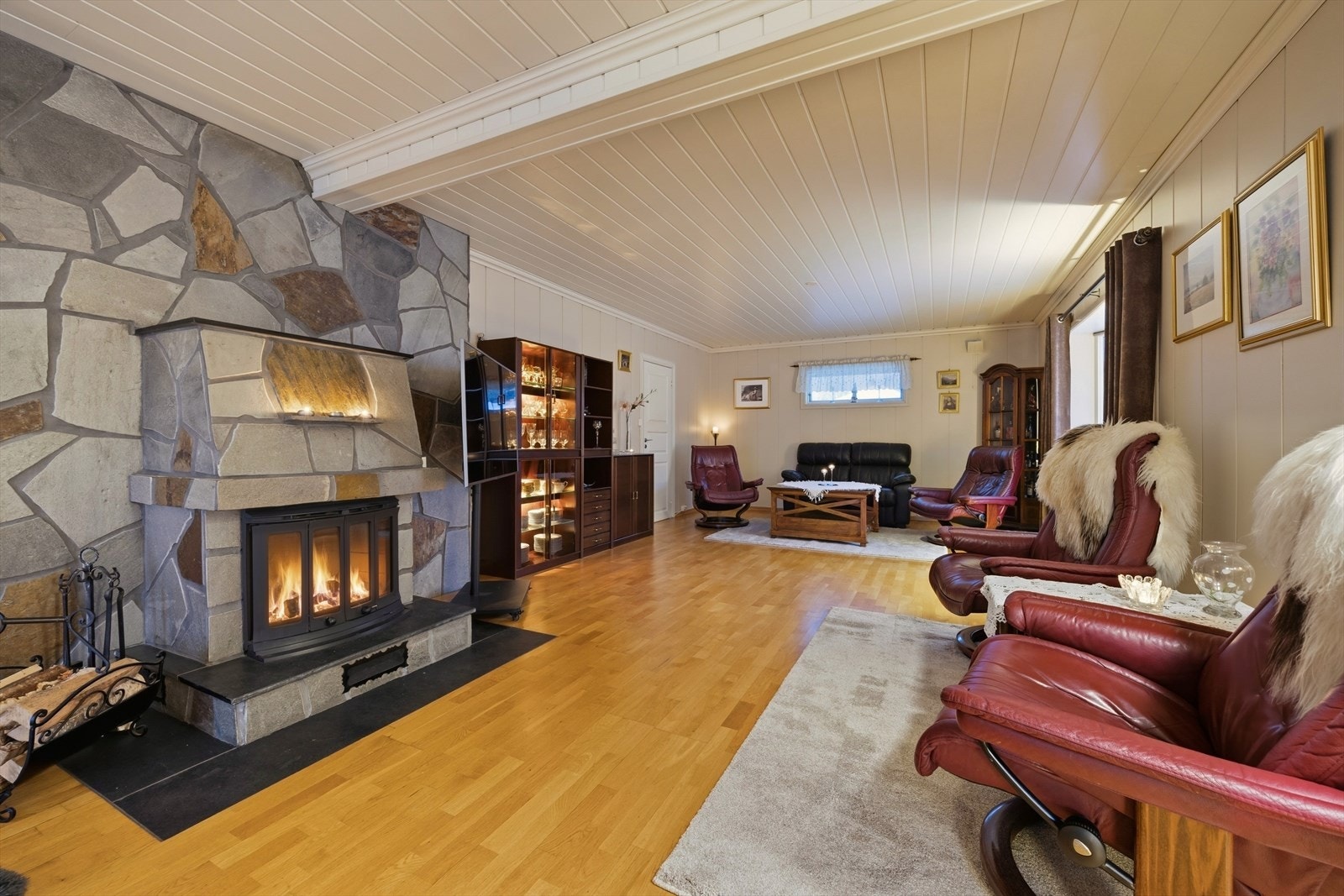 Allrommet har lysmalte overflater og parkett på gulvet. Midt i rommet står også en flott peis med innsats. Galleribilde