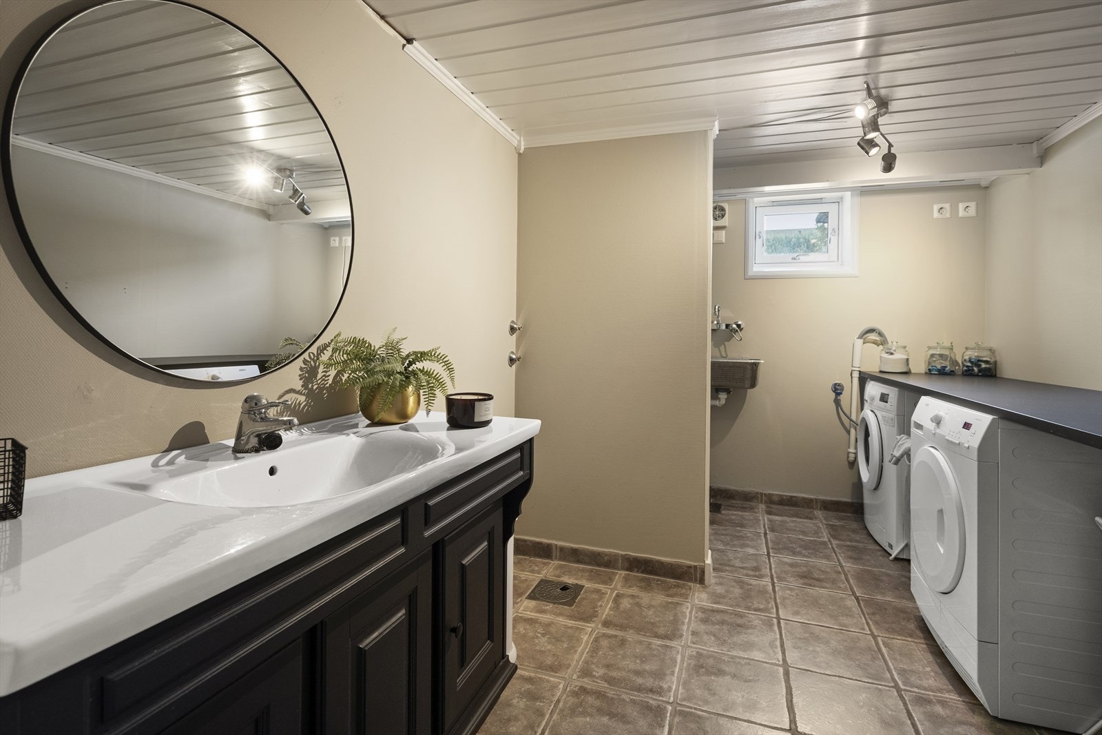 Det er separat vaskerom/taolettrom i boligens underetasje, med fliser på gulv Galleribilde