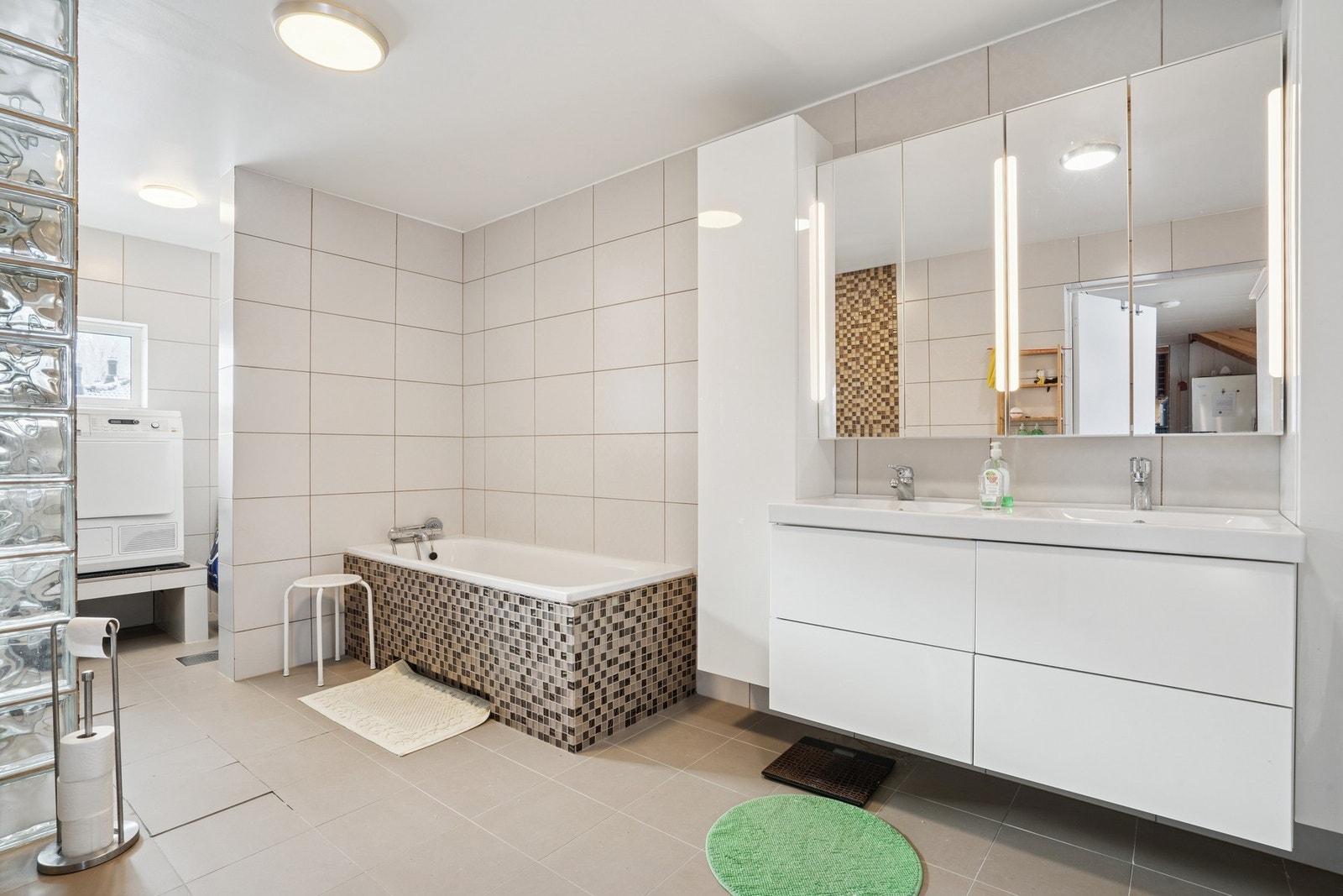 Romslig bad/vaskerom med flislagte gulv og vegger. Galleribilde