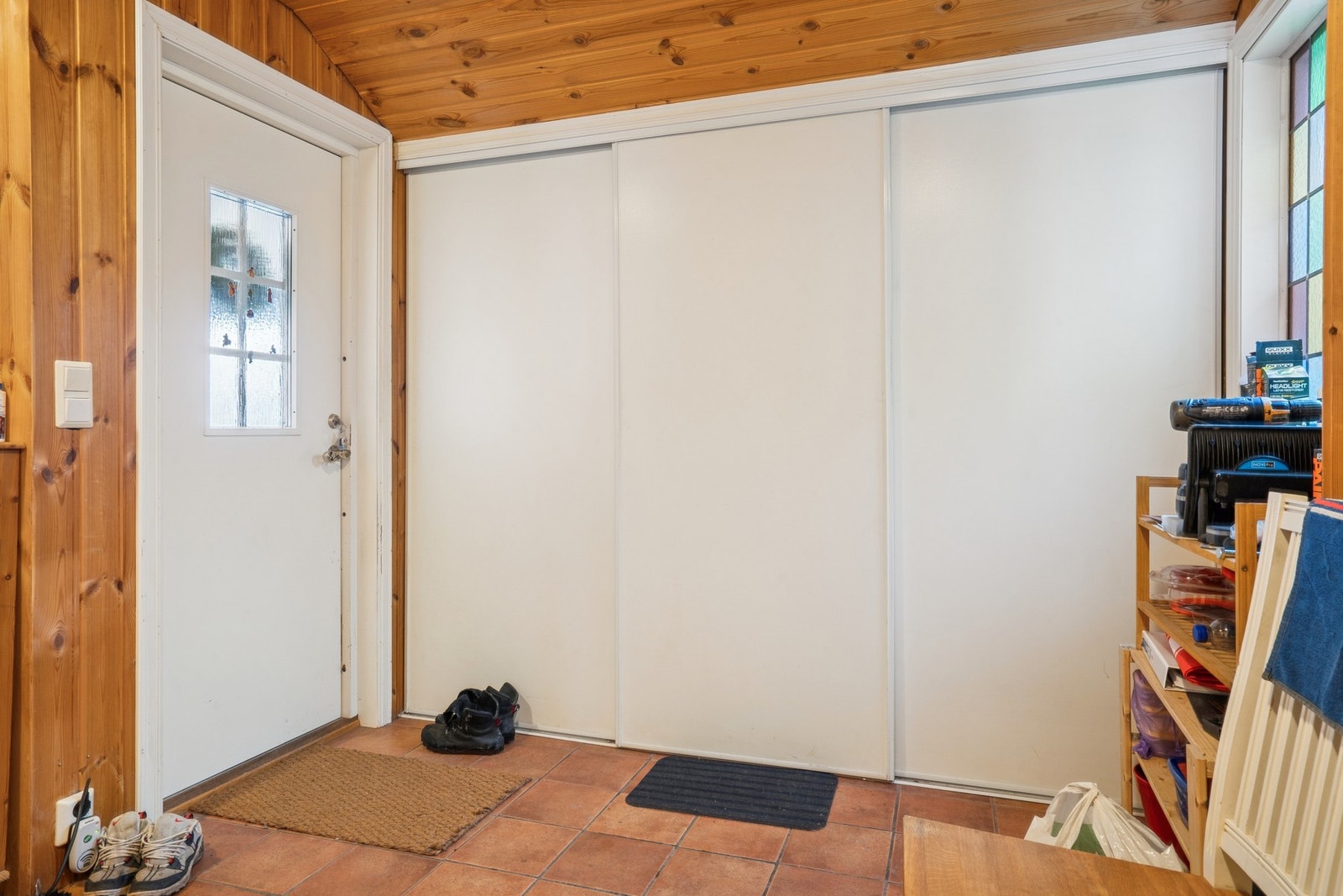 Entré med flislagt gulv og panel på vegger og i himling. Galleribilde