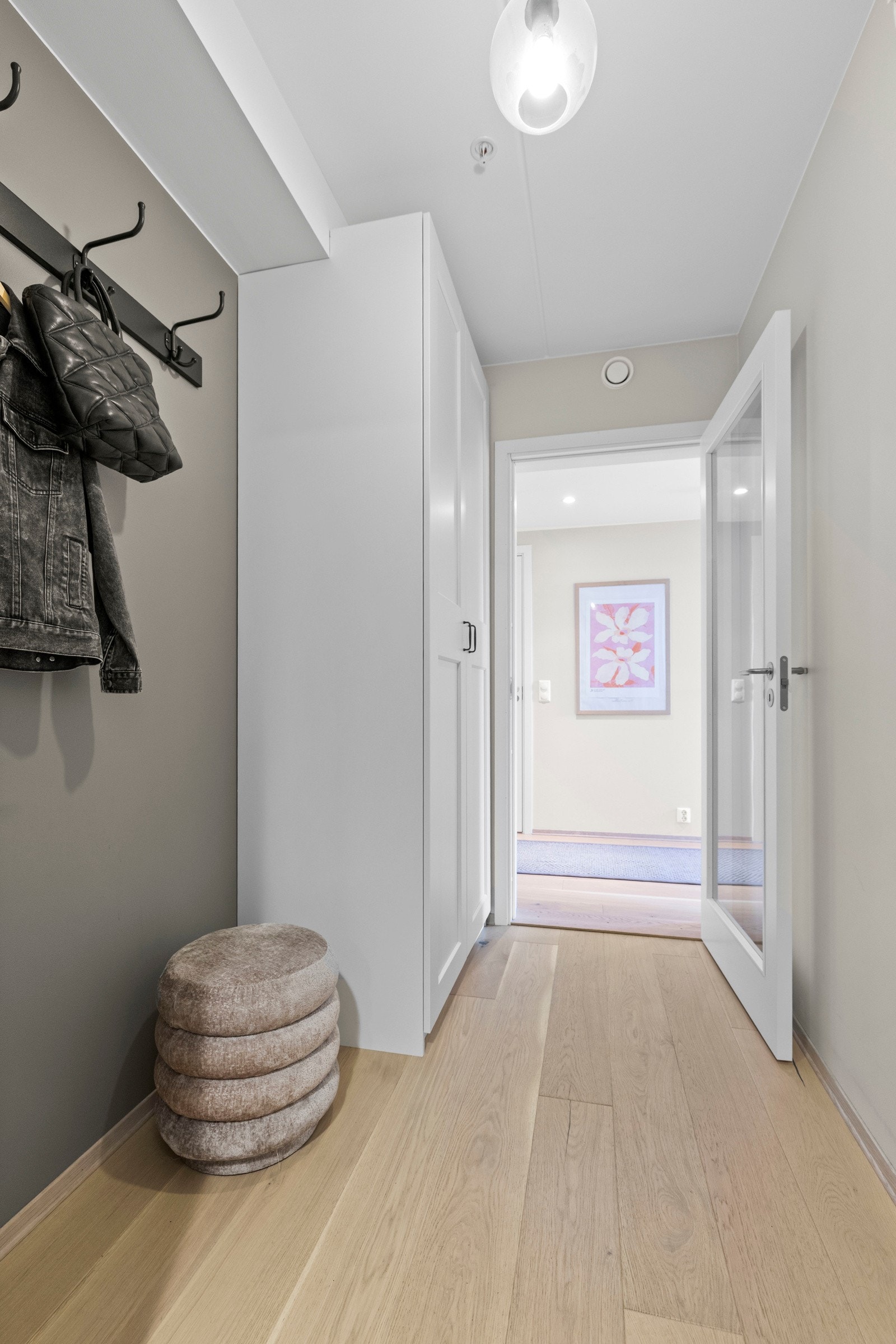 Velkommen inn i en lys og innbydende entré! Her møtes du av parkett på gulv og malte vegger som gir et stilrent førsteinntrykk. Den praktiske garderobeløsningen gjør det enkelt å holde orden på yttertøy og sko, og setter tonen for resten av leiligheten. Galleribilde