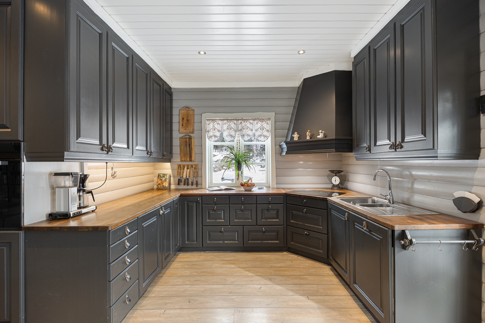 Innredningen har sorte, profilerte fronter, takhøye skap og solid, gyllen heltrebenkeplate med nedfelt kum i stål. Galleribilde