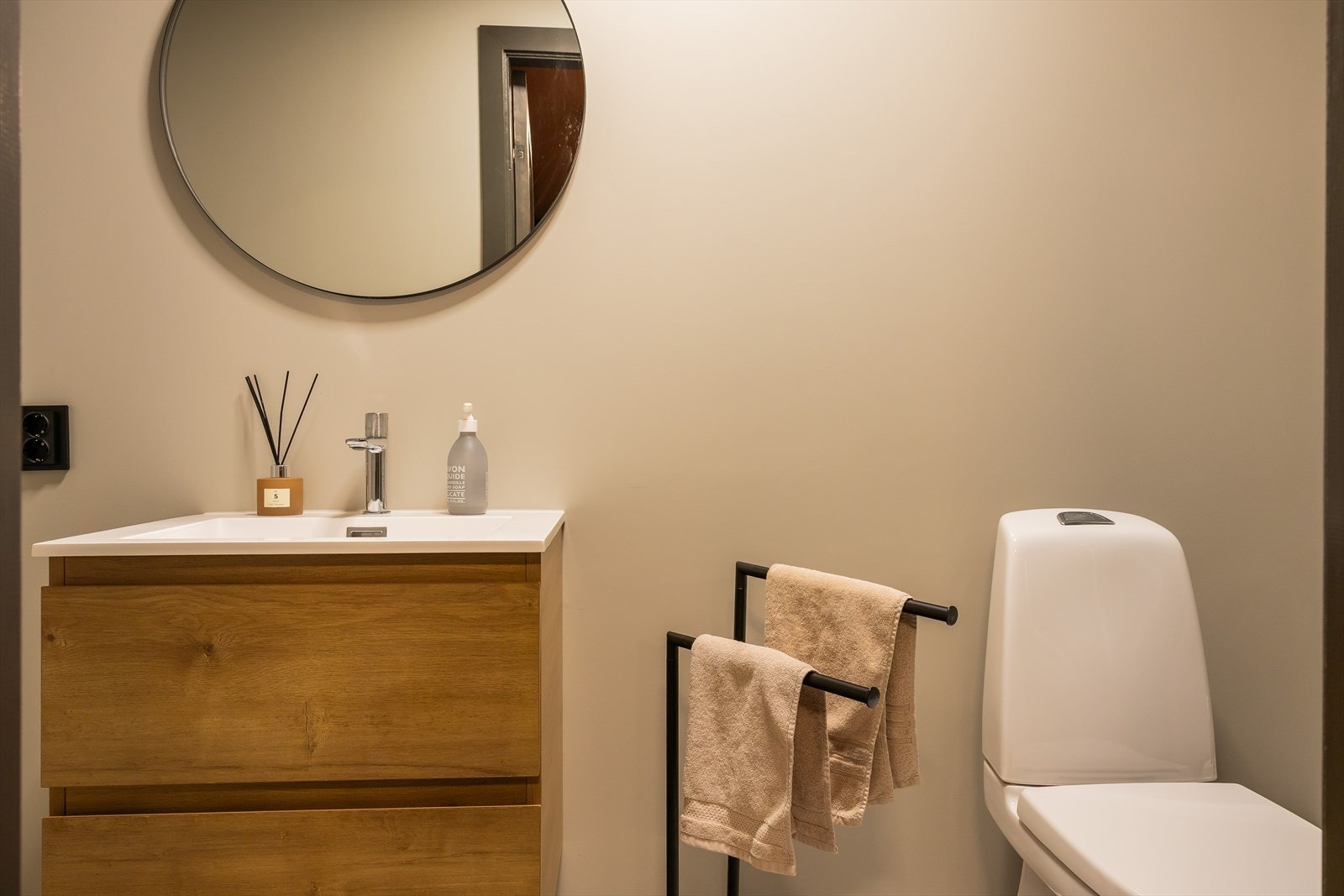 Bad inn fra gangen med dusjkabinett, servant i helstøpt plate, benkeskap med glatte fronter. Galleribilde