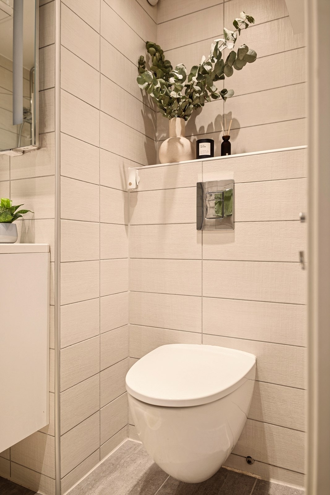 Innredningen består av servantskap med glatte, malte fronter og heldekkende servant, samt speil med lysarmatur over. Veggmontert klosett gir et moderne uttrykk og gjør renholdet enklere. Galleribilde