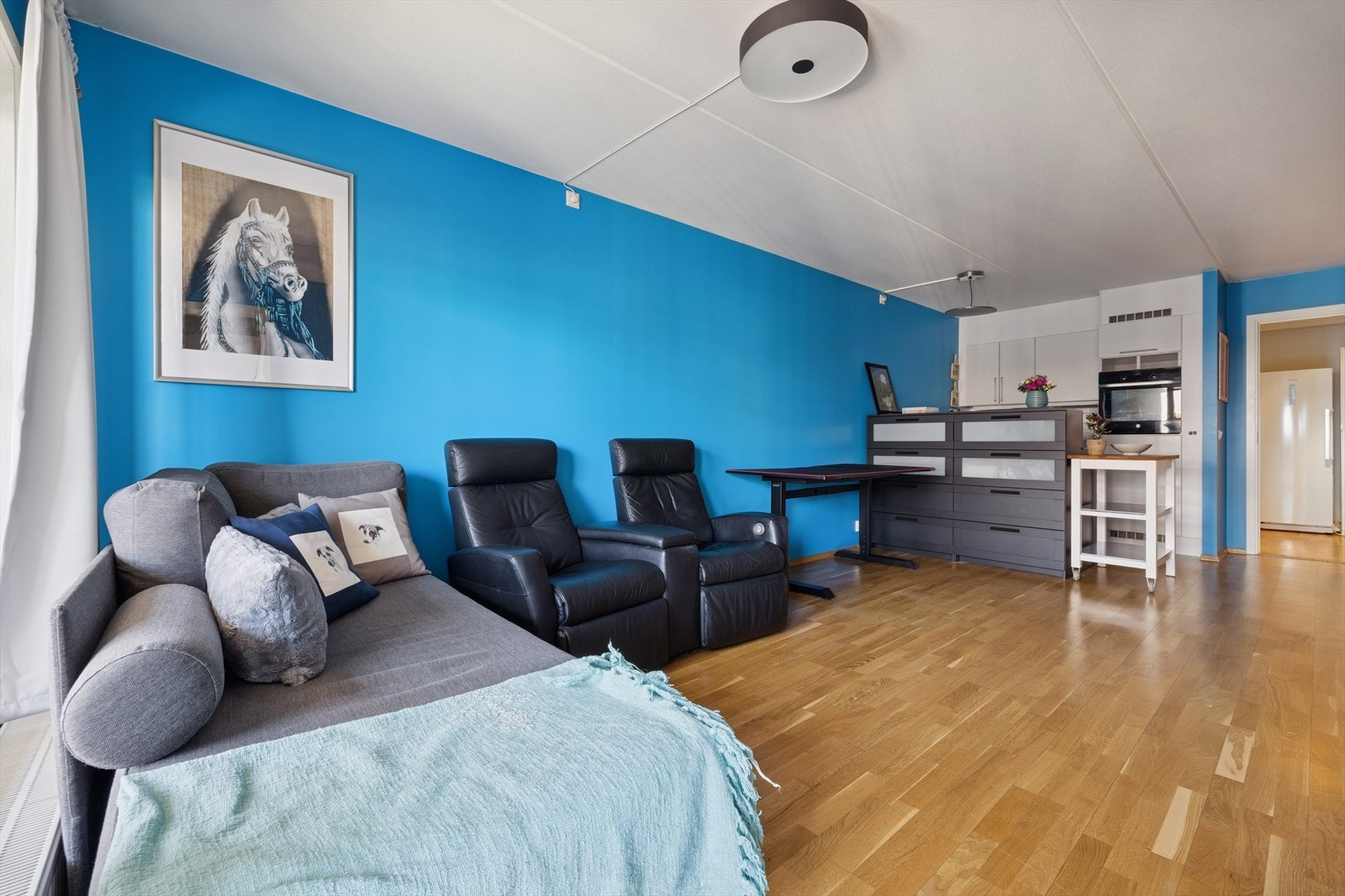 Kjøkkenet har en smart og funksjonell utforming med innredning langs én vegg og en praktisk barløsning mot stuen, som gir ekstra oppbevaringsplass Galleribilde