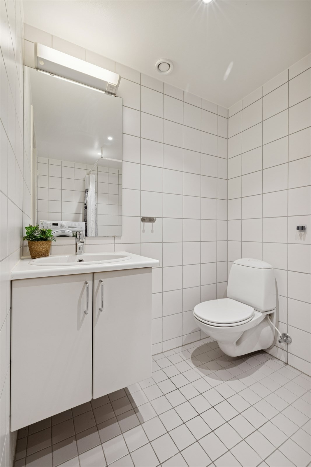 Badet er helfliset med hvite fliser på både gulv og vegger, og har elektriske varmekabler som gir god komfort Galleribilde