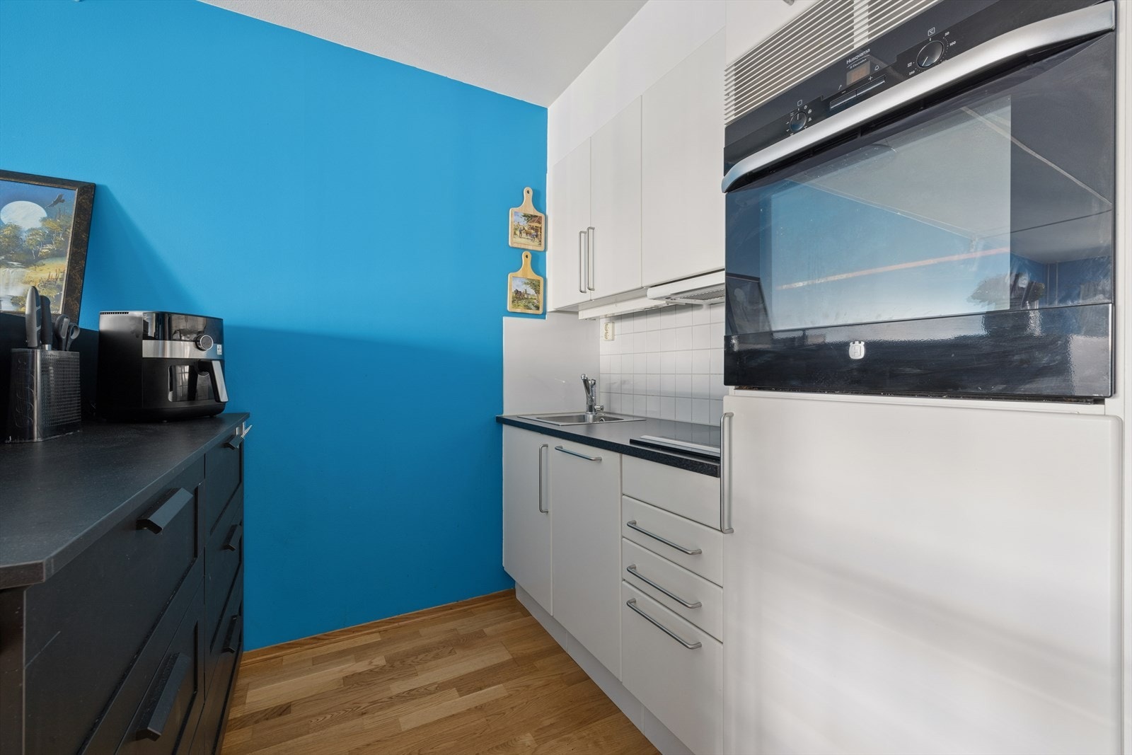 Kjøkkenet har innredningen med glatte fronter, kombinert med laminat benkeplate, oppvaskkum med ettgreps blandebatteri og ventilator over kokesonen Galleribilde