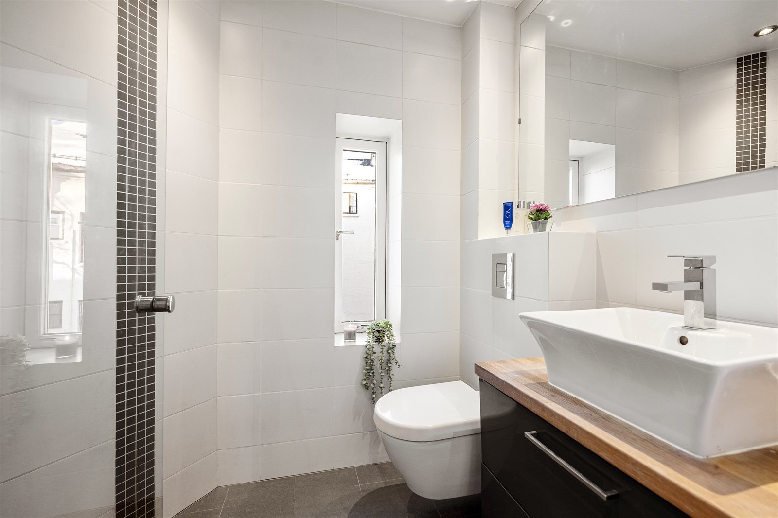 Lekker bad som med mørke fliser med varmekabler under på gulvet og hvite fliser på veggene. Galleribilde